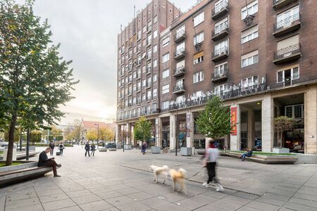 Budapest, Hungary - November 01, 2018:  Madach Square or MadÃ¡cs TÃ©r, street view with people passing by, reading on bench, and walking dogs on a sunny afternoon in Budapest, late Autumn.のeditorial素材