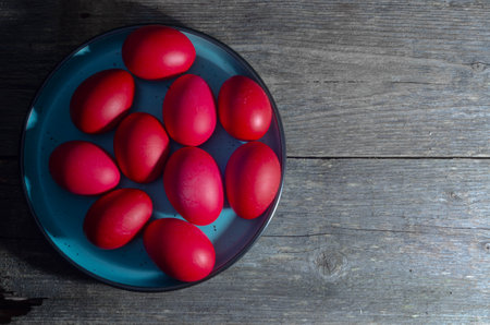 Red Easter eggs on a blue plate on a rustic wooden backgroundの写真素材
