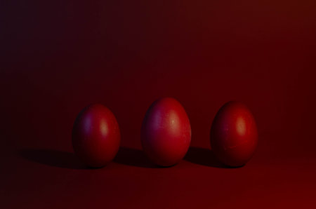 Three red easter eggs on a red background with copy space.の写真素材