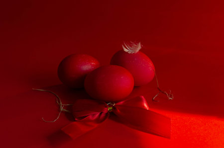 Red Easter eggs with red ribbon on red background. Happy Easter concept.の写真素材