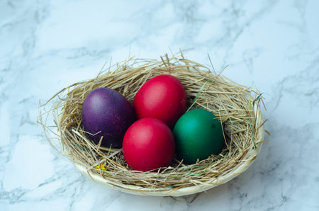 Colorful easter eggs in a basket on a white marble backgroundの写真素材