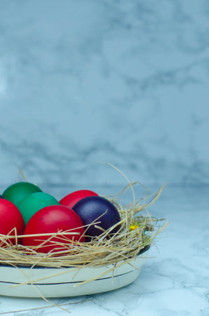 Colorful easter eggs in a bowl on a white marble backgroundの写真素材