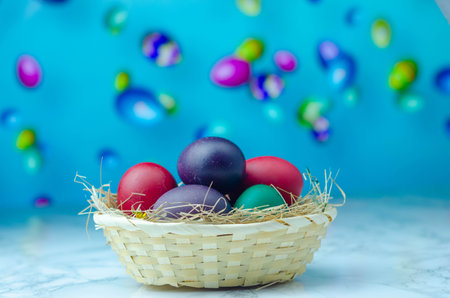 Colorful easter eggs in a basket on a blue background.の写真素材