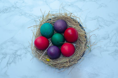Colorful easter eggs in a nest on a white marble backgroundの写真素材