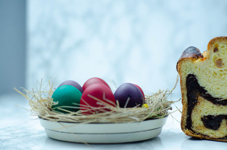 Easter cake and colored eggs in a nest on a white backgroundの写真素材