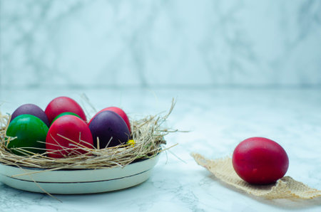 Colorful Easter eggs in a nest on a white marble background.の写真素材