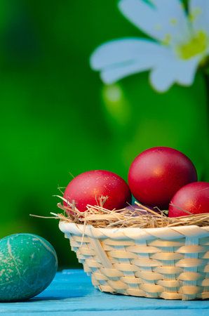 Easter eggs in a basket on a wooden table with a green backgroundの写真素材