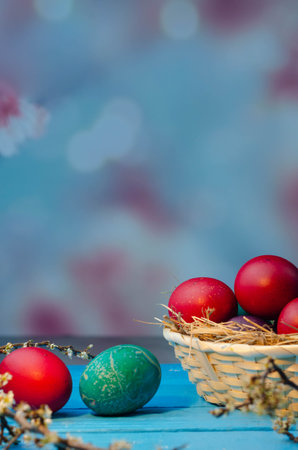 Colorful Easter eggs in a basket on a blue wooden background.の写真素材
