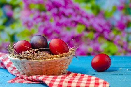Easter eggs in a basket on a blue wooden table with a blurred backgroundの写真素材
