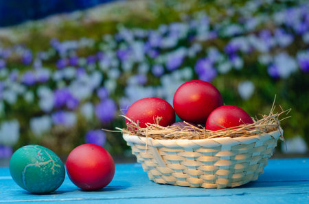 Colorful easter eggs in a basket on a blue wooden tableの写真素材