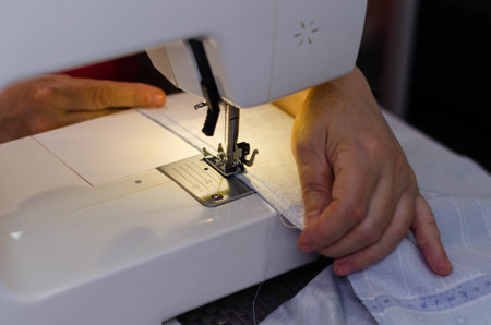 Close-up of a woman using a sewing machine at home.