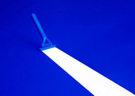Blue plastic scraper on a blue background with a white line.の写真素材