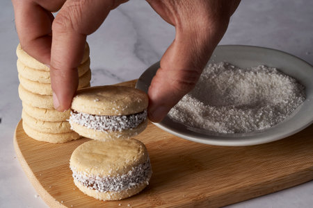 hand stacking alfajor of cornstarch and dulce de leche. Dulce de leche is also known as dulce de...