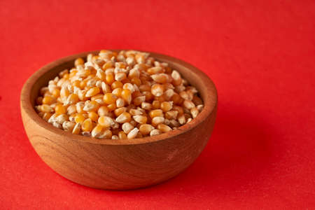 Field Corn in wooden bowl on red background popcornの写真素材