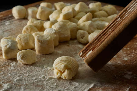 kneading gnocchi on wooden board with flour