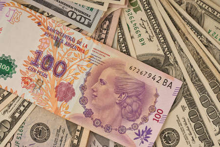 100 Argentine peso bill on dollar billsの写真素材