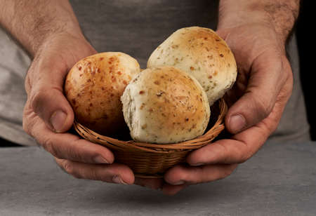 man's hands offering flavored breads in a basket
