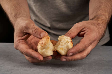 man's hand breaking piece of flavored bread