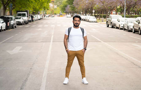 latin man standing in the middle of the street with his hands in his pockets and a backpack in Buenos Airesの写真素材