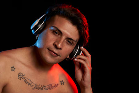 portrait latin man with headphones listening to music with tatooの写真素材