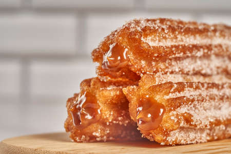 three churros filled with dulce de leche caramel on a wooden board
