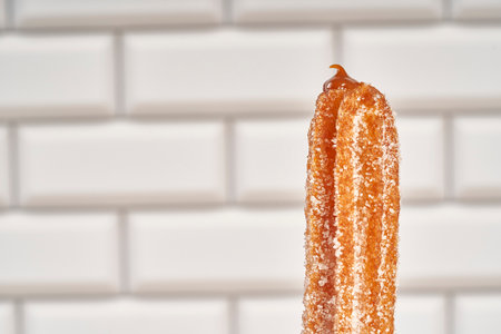 churro filled with dulce de leche on a white ceramic background with copy spaceの写真素材
