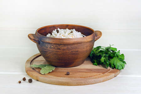 Homemade sauerkraut in a wooden bowl. Dish is decorated with a parsley, bay leaf and peppercornsの写真素材