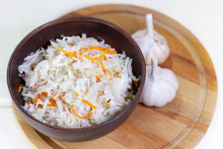 Sauerkraut with carrots in bowl on wooden background. Marinated vegetablesの写真素材