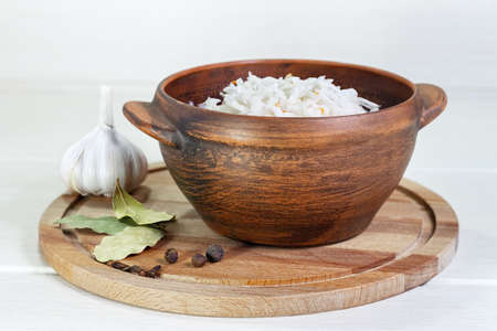 Sauerkraut in clay bowl. Homemade with carrot and salad cabbage on a wooden tableの写真素材