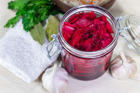 Healthy fermented canned cabbage sauerkraut with beetroot and herbs in a glass jar top viewの写真素材
