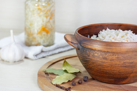 Fermented vegetables sauerkraut on wood background. Sauerkraut with carrot in wooden bowl, garlic, spices, cabbageの写真素材