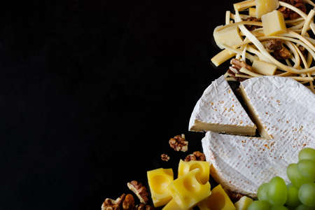 Assortment of cheeses and walnuts on a black table. Top view. Space for you text.の写真素材