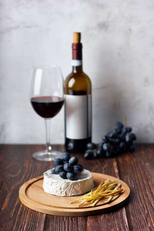Cheese plate served with red wine and grape. Assorted cheeses Camembert and smoke cheese.の写真素材