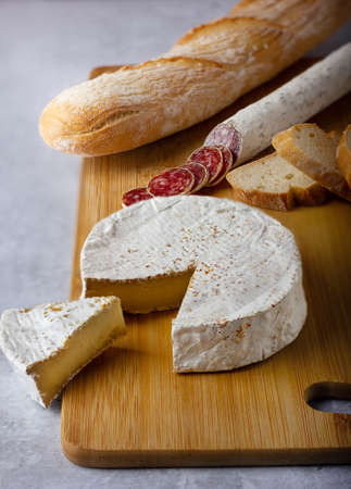 Spanish sausages cut in slices and cheese camembert on a wood board.の写真素材