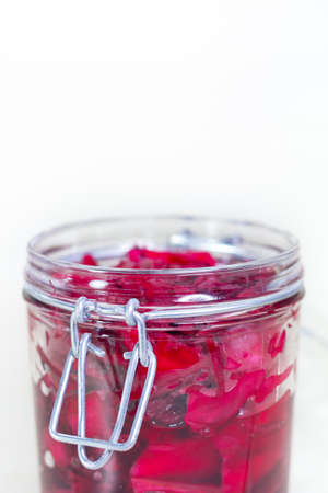 Fermented red cabbage lies in a glass jar. Sauerkraut with spices. Copy space.