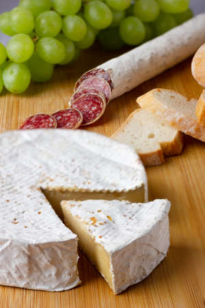 Spanish sausages cut in slices and cheese camembert on a wood boardの写真素材