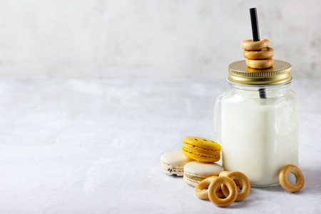 Baked bagels, macaroon and milk in mason jar on stone backgroundの写真素材