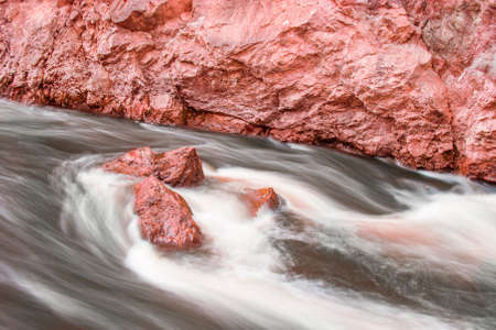 Flowing water around red stones in Lapland. Long exposure to get blurry water.の写真素材