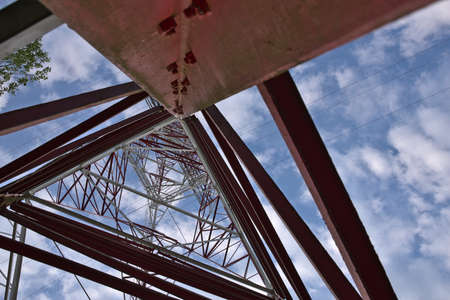 Power pole on the background of a blue sky with white clouds. High voltage line. Steel structural...