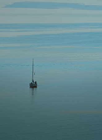 Sailboat on a turquoise water surface with reflection. River sailing.の写真素材