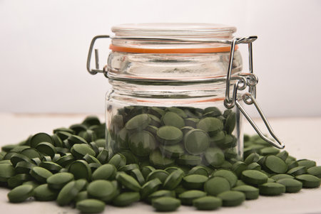 Green tablets of bio chlorella in a glass jar. A health-promoting dietary supplement rich in vitamins. Chlorella vulgaris.の写真素材