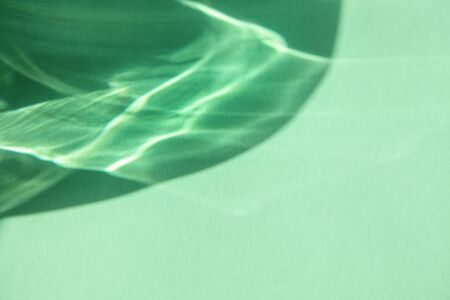 Trendy mint colored abstract background with light and shadows caustic effect. Light passes through a glass.の写真素材