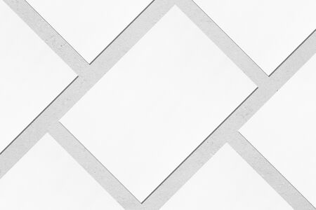 Close up of empty white rectangle poster mock ups lying diagonally with soft shadow on neutral light grey concrete background. Flat lay, top view. Open composition.の写真素材