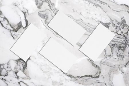 Four white rectangle business card mockups with soft shadows lying on grey marble background. Flat lay, top viewの写真素材