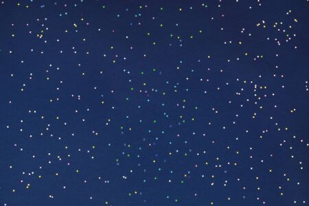 Holographic foil stars confetti sparse on dark blue background. Simple holiday concept. Winter festive backdrop. Top view, flat layの写真素材