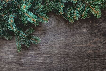 Natural Christmas background with border of fluffy green fir branches on a textured dark brown wood...