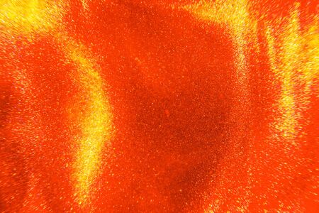 Abstract elegant, detailed bright red and gold glitter particles flow with shallow depth of field underwater. Holiday magic shimmering luxury background. Festive sparkles and lights. de-focused.の写真素材