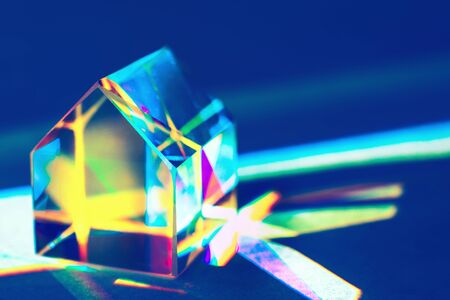  Closeup of colorful glass prism house on trendy blue background with rainbow light refraction and...