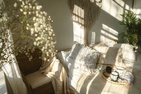 Cozy boho style sunny bedroom with light and shadows and close up of white gypsophila flowers. Authentic real life interiorの写真素材