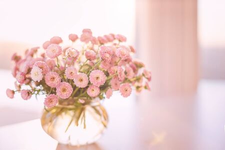 Close-up of small pink flowers bouquet in glass vase with blurred soft focused light background by the windowの写真素材